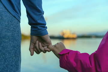 father and daughter walking along the river bank holding hands