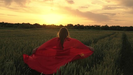 Young superhero girl outdoors. Slow motion. Child playing in red coat. Happy child girl plays...