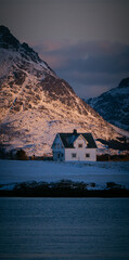 little house in front of the high fjords of Lofoten Norway in the evening light