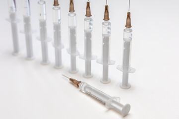 syringes with needles lined up in a row show a graph of ever fewer vaccinations, there is also one...