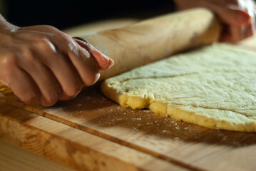 Baker's hands working the flour dough on a wooden board