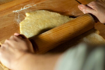 Baker's hands working the flour dough on a wooden board