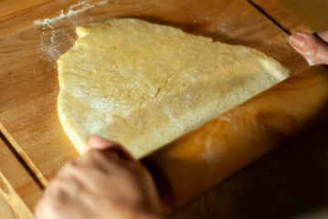 Baker's hands working the flour dough on a wooden board