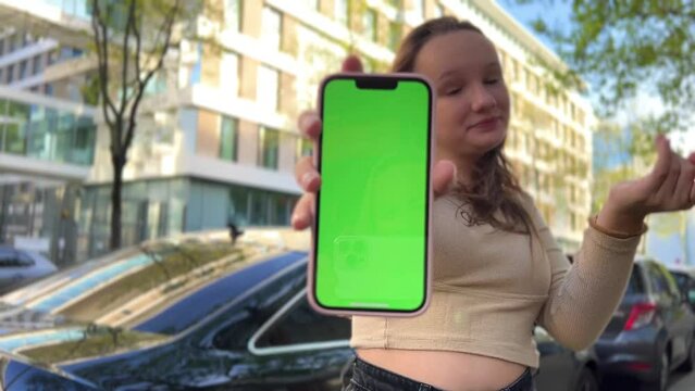 Teenage girl with loose hair brown hair brown hair dances with phone rejoices on the screen of lameness green screen beige background. High quality 4k footage
