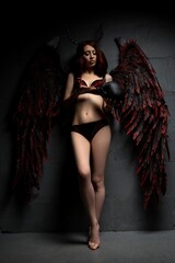 Sexy woman in provocative fallen angel concept with skull