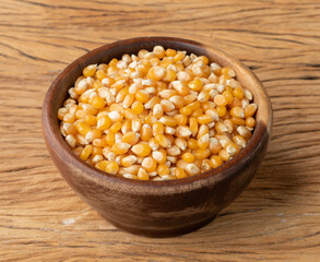 Dried corn or popcorn grains in a bowl over wooden table