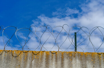 Barbed wire fence on a high wall. Protection of an important object. Close-up view.