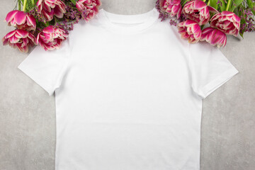 White womens cotton t-shirt mockup with pink tulips flowers on gray concrete background. Design t...
