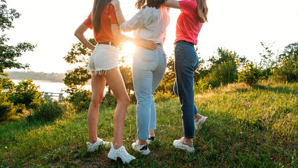 Group of girl friends jumping outdoors on sunset nature. Young multi-ethnic hipster friends dancing...