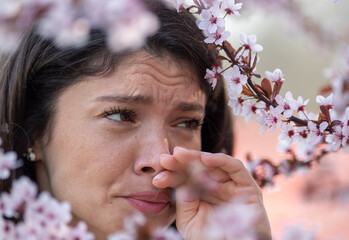 Girl having itchy nose from blooming tree in spring