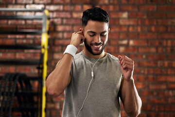 Nothing boosts your workout like really good beats. Shot of a young man stretching using earphones...