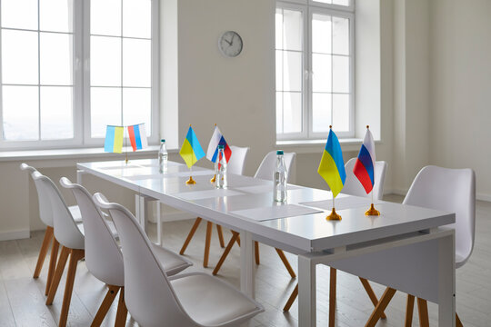 Press Room. Interior Of Room For Diplomatic Meeting Between Representatives Of Ukraine And Russia. Meeting Room Without People With Empty Chairs And Table With Small Flagpoles With National Flags.