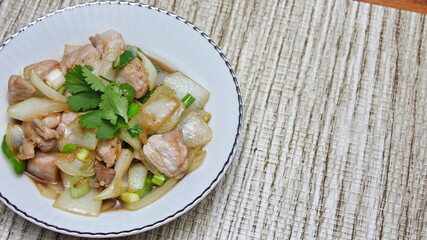 Stir-fried pork with chilli with onions and spring onions served in a white plate, Stir-fried pork with chilli is a popular Thai dish that Thai people eat.