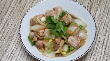 Stir-fried pork with chilli with onions and spring onions served in a white plate, Stir-fried pork with chilli is a popular Thai dish that Thai people eat.