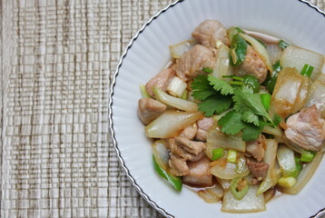 Stir-fried pork with chilli with onions and spring onions served in a white plate, Stir-fried pork with chilli is a popular Thai dish that Thai people eat.