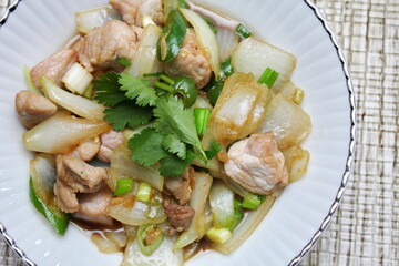 Stir-fried pork with chilli with onions and spring onions served in a white plate, Stir-fried pork with chilli is a popular Thai dish that Thai people eat.