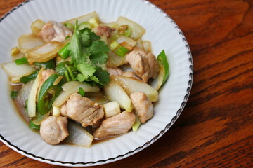 Stir-fried pork with chilli with onions and spring onions served in a white plate, Stir-fried pork with chilli is a popular Thai dish that Thai people eat.