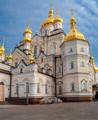 Fototapeta na wymiar Majestic Christian Orthodox religious building. Arched windows, golden domes and crosses, patterned walls. Holy Dormition Pochaiv Lavra in Ukraine.