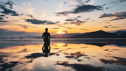 Fototapeta na wymiar Silhueta de um homem se exercitando na beira da praia durante pôr do sol