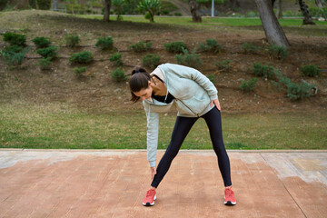 brunette sportswoman stretching in park