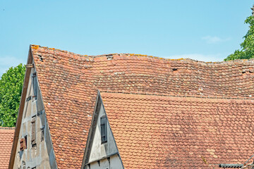 A closeup of red tile roofs, one that is sagging, on a dilapidated building hundreds of years old, Rothenberg, Germany. - obrazy, fototapety, plakaty