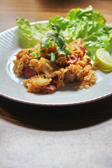 Pork and sausage fried rice served in a plate with lettuce and coriander garnish. Fried rice is a street food that is sold in Thailand.