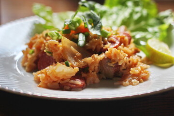 Pork and sausage fried rice served in a plate with lettuce and coriander garnish. Fried rice is a street food that is sold in Thailand.