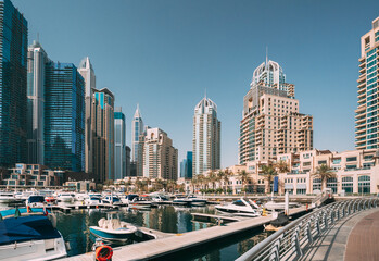 Fototapeta na wymiar Yachts are moored at city pier, jetty in Dubai Marina. Cityscape skyline. View of glass skyscrapers in Dubai.