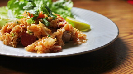 Pork and sausage fried rice served in a plate with lettuce and coriander garnish. Fried rice is a street food that is sold in Thailand.