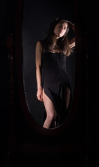 Woman in Black Dress Looking at Reflection in Mirror