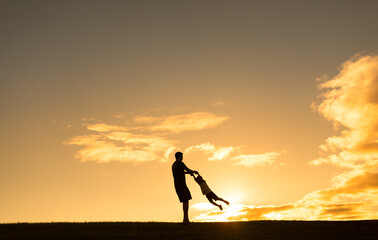 Father and child silhouette playing in the sunset 