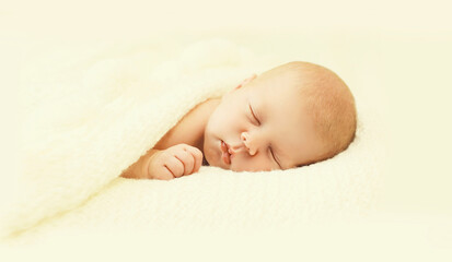 Close up portrait of infant sweet sleeping on white bed at home