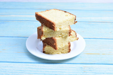 Homemade vanilla cake, displayed on a plate and portioned and on a wooden background