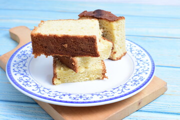 Homemade vanilla cake, displayed on a plate and portioned and on a wooden background