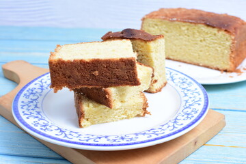 Homemade vanilla cake, displayed on a plate and portioned and on a wooden background