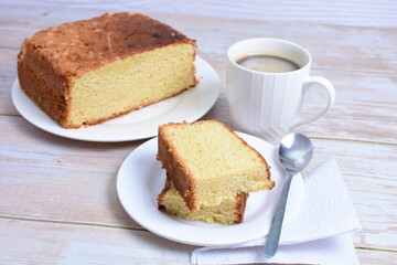 Homemade vanilla cake, displayed portioned and traces of coffee in the background on wood