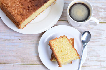 Homemade vanilla cake, displayed portioned and traces of coffee in the background on wood