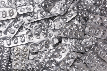 used empty pill blister packs, silver medicine packets background, treatment and medication concept