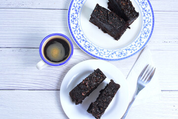 Traditional black ponque, with raisins, red wine flavor accompanied by a cup of coffee on a wooden background