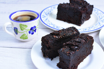 Traditional black ponque, with raisins, red wine flavor accompanied by a cup of coffee on a wooden...