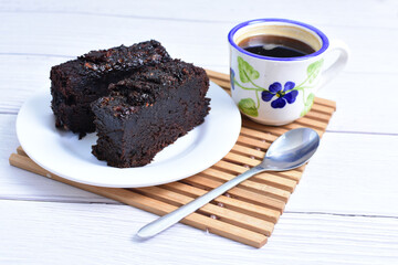 Traditional black ponque, with raisins, red wine flavor accompanied by a cup of coffee on a wooden background