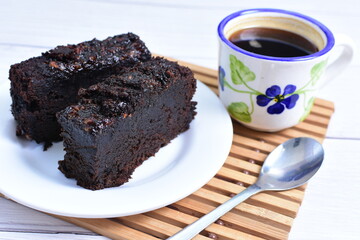 Traditional black ponque, with raisins, red wine flavor accompanied by a cup of coffee on a wooden background