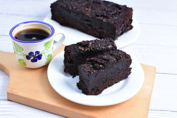 Traditional black ponque, with raisins, red wine flavor accompanied by a cup of coffee on a wooden...