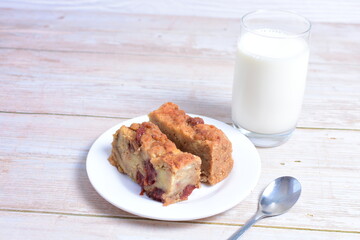 Fluffy bread cake with guava flavor accompanied by a glass of milk on a wooden background