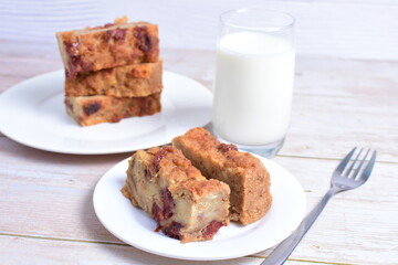 Fluffy bread cake with guava flavor accompanied by a glass of milk on a wooden background