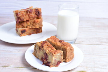 Fluffy bread cake with guava flavor accompanied by a glass of milk on a wooden background