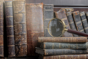 Vintage book and magnifying glass on wooden background.