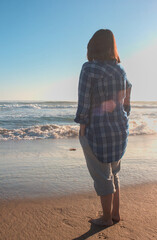 mujer joven con lentes disfrutando la playa, fotografiando y mirando el mar