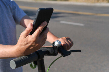 Unrecognizable man looking at his phone to ride his electric kick scooter