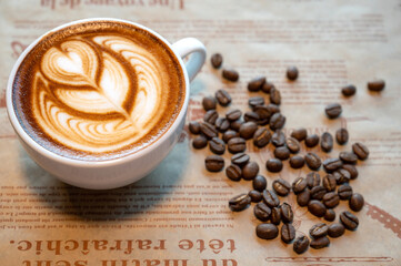 Hot latte coffee in white cup with  coffee beans placed on dark brown wood table, bakery and natural food, with light and dark,Italian and french cafe and croissant.